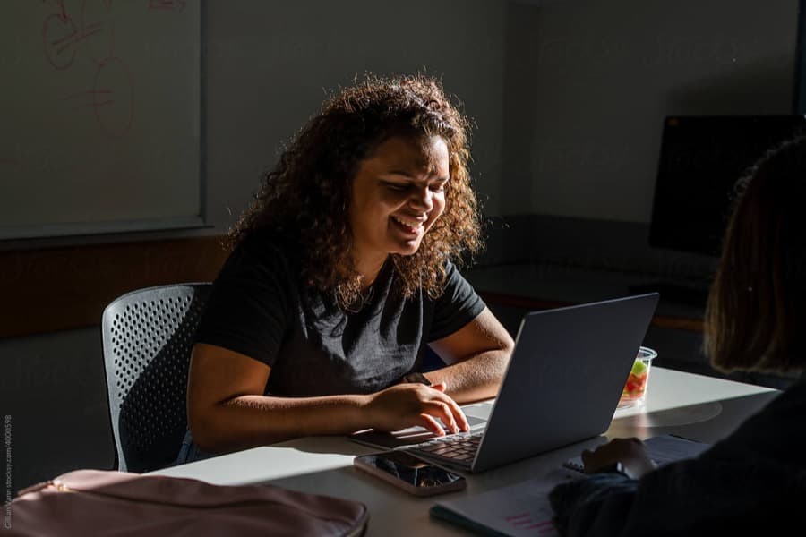 Student smiling while studying on a laptop