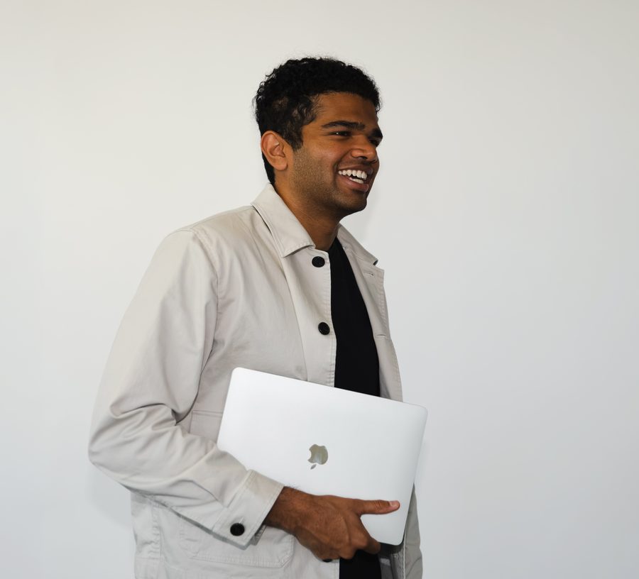 Tejas from Sales laughing with a laptop tucked under one arm